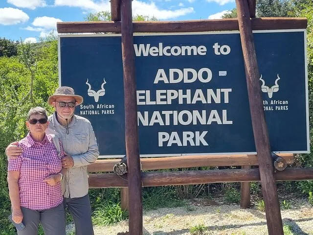 Ein Paar posiert vor dem Eingangsschild des Addo Elephant National Park.